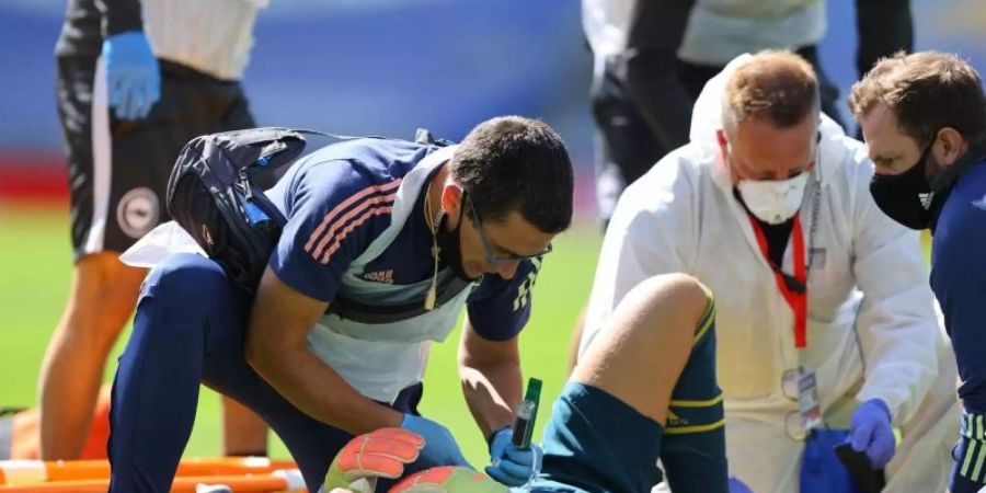 Arsenal-Torwart Bernd Leno (M) wird von medizinischem Personal behandelt, nachdem er sich verletzt hat. Foto: Richard Heathcote/Nmc Pool/PA Wire/dpa