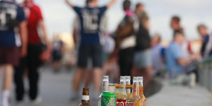 Menschen haben sich am Abend an der Promenade am Strand von Arenal versammelt und trinken Alkohol.