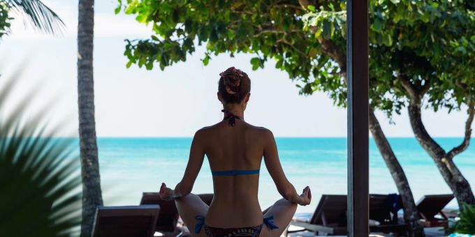 Gehen Sie raus und meditieren Sie wenn es geht, bevor Ihnen die Hutschnur reisst. Frau in Lotuspose am Meer.