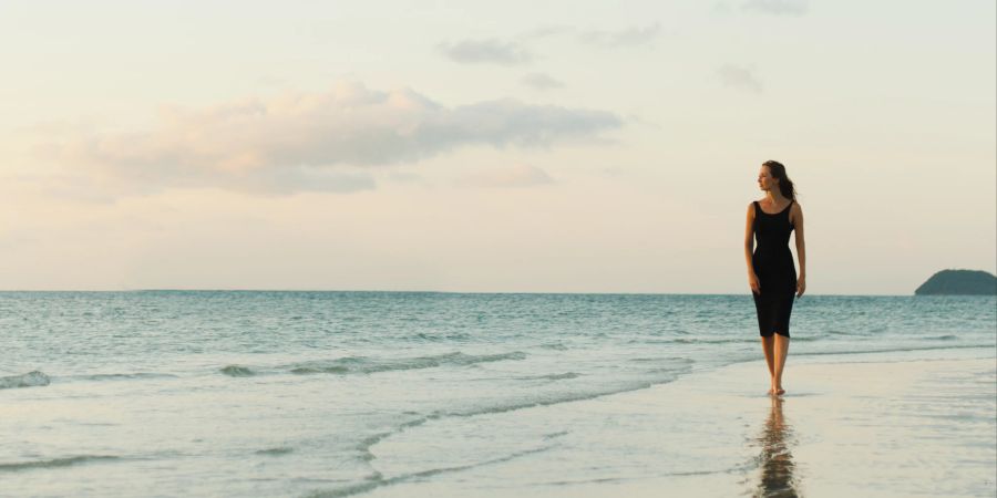 frau spaziert an strand entlang