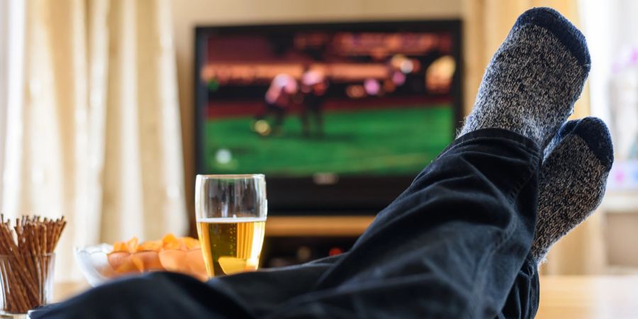 Hochgelegte Füsse vor dem TV, Bier, Snacks