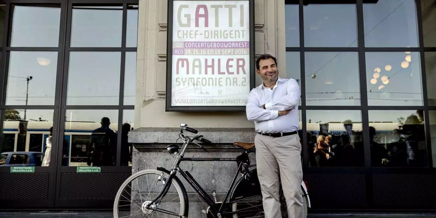 Daniele Gatti, italienischer Dirigent, lächelt neben dem Fahrrad, das ihm zum Start seiner neuen Aufgabe als Chefdirigent des Royal Concertgebouw Orchestra geschenkt worden ist. Gegen die Entlassung wegen Anschuldigungen von sexuellem Fehlverhalten entliess ihn das Amsterdamer Orchester.