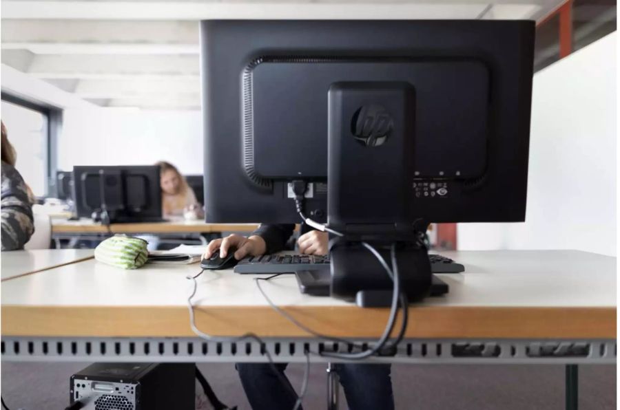 Computerbildschirm von hinten mit Schülerin davor - Keystone