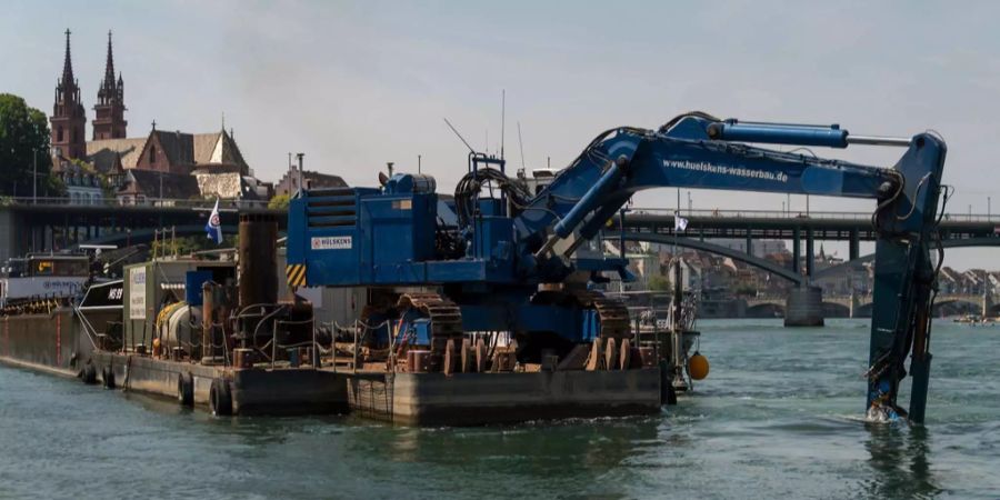 Ein Bauschiff mit einem Bagger ist im Rhein positioniert für die Bauarbeiten zur Korrektur der Schifffahrtsrinne.