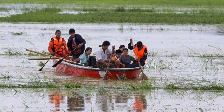 Mehrere Personen paddeln mit einem Boot durch einen überfluteten Bereichs in Yedashe nahe Naypyitaw.