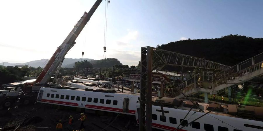 Rettungskräfte versuchen mit einem Kran den verunglückten Zug in Taiwan zu entfernen.