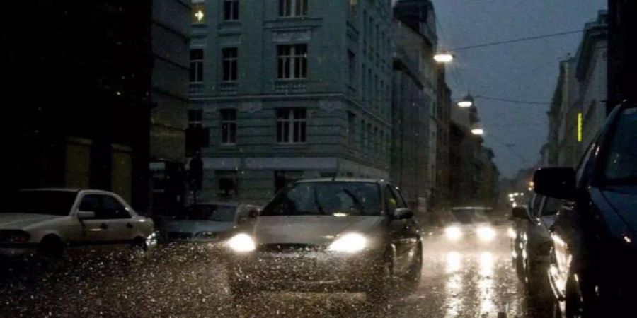 Ein Auto fährt bei heftigem Regen durch die Strassen Wiens.