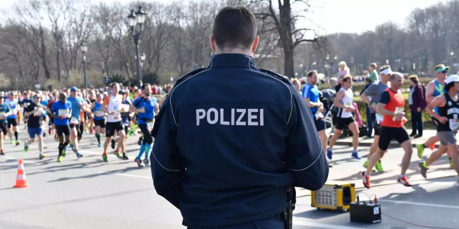 Berliner Halbmarathon. Ein Polizeibeamter steht an der Laufstrecke.