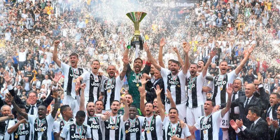 Der Torhüter von Juventus, Gianluigi Buffon (M), hält den Siegerpokal hoch während das Team um ihn herum jubelt.