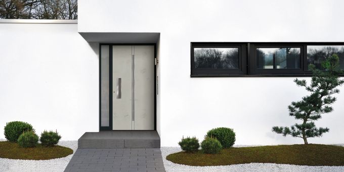 Schlichte, geradlinige Haustüren mit Art-Beton sind derzeit angesagt. Haus Front Haustür Beet Kies Beton
