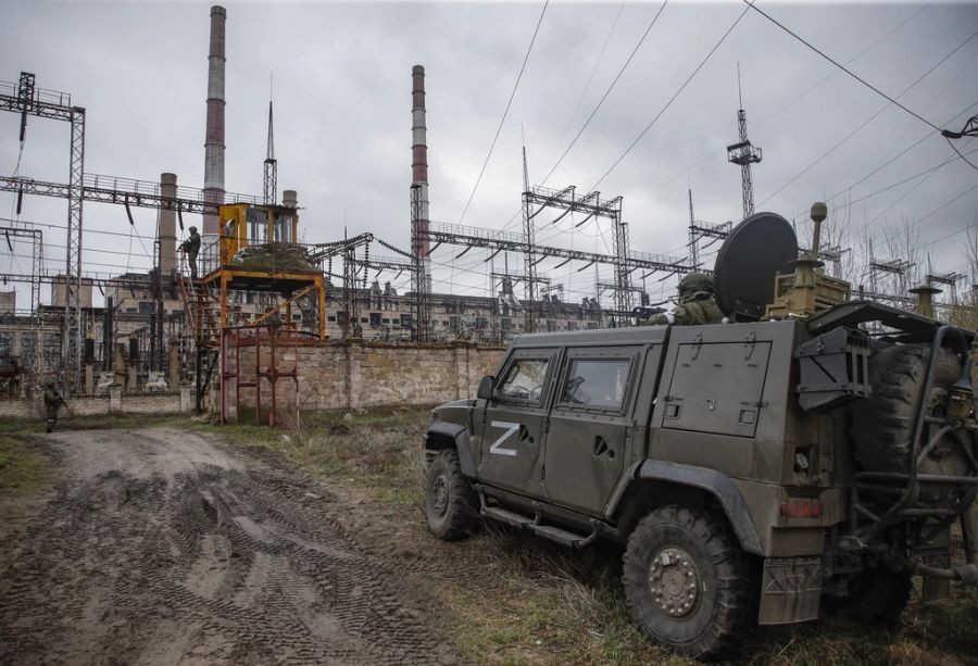 Ein Bild, das während eines vom russischen Militär organisierten Besuchs in Luhansk am 13. April 2022 aufgenommen wurde, zeigt russische Soldaten, die den Eingang des Kraftwerks Luhansk in Schtschastia bewachen.