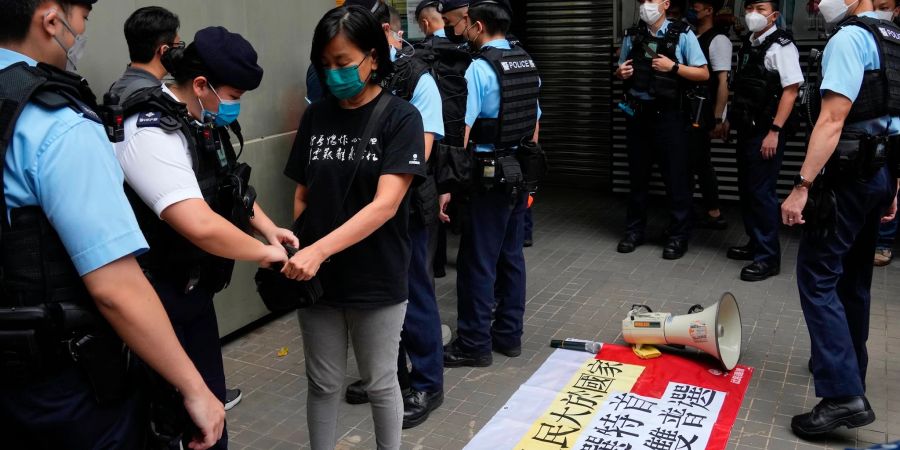 Eine Demonstrantin wird von Polizeibeamten durchsucht.