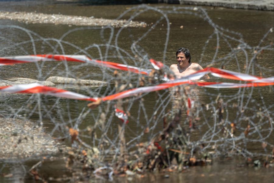 Ein Mann badet im Fluss Cassarate hinter Stacheldrahtzaun, fotografiert im Vorfeld der Ukraine Recovery Conference in Lugano.