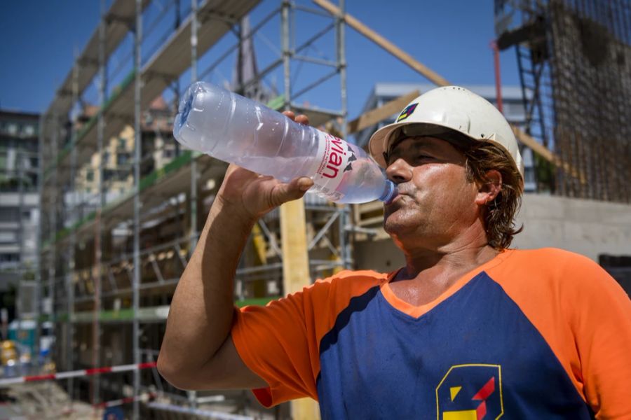 Ein Bauarbeiter trinkt aus einer Wasserflasche.