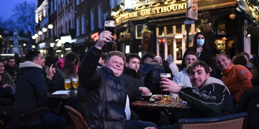 Junge Menschen sitzen draussen in einem englischen Pub. Bei einem Rauchverbot dürfte hier nicht mehr gepafft werden.