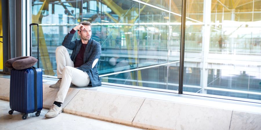 Mann wartet genervt am Flughafen.