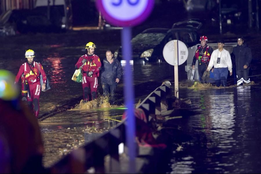 Rettungskräfte begleiten Menschen aus ihren Häusern in Valencia.