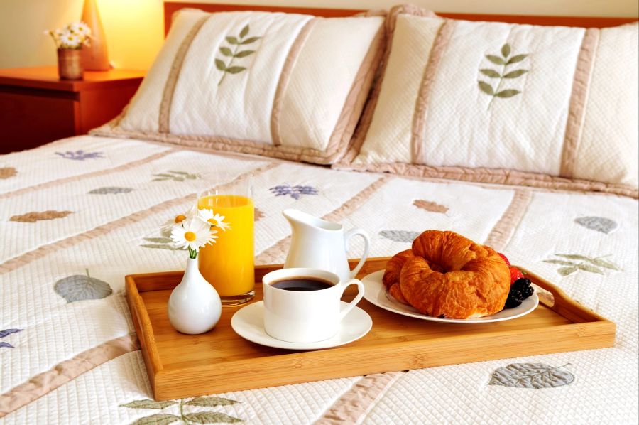 Tablett mit Frühstück auf dem Bett im Hotelzimmer