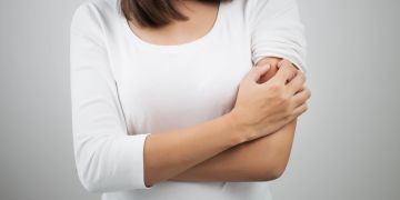 Person kratzt sich am Arm