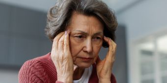 Nachdenkliche Frau fasst sich an die Schläfen