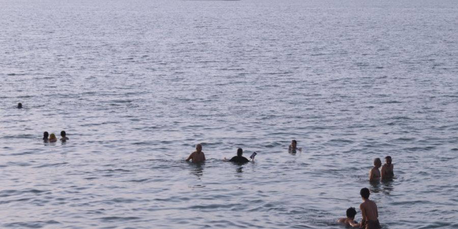dpatopbilder - Anwohner schwimmen, während Fracht- und Handelsschiffe in der Straße von Hormus vor Bandar Abbas im Iran vor Anker liegen. Foto: Amirhosein Khorgooi/ISNA/AP/dpa