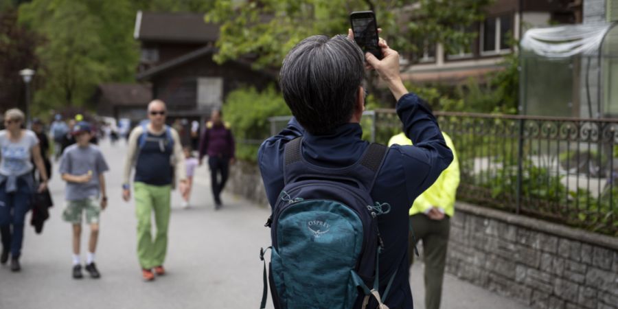 Ein Tourist fotografiert ein Haus in Lauterbrunnen. Die Touristenmassen, vor allem in der Hochsaison, sorgen nicht nur für Freude, sondern auch für manchen Frust. (Archivbild)