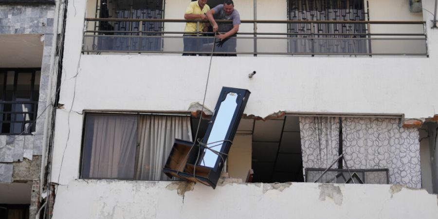 Ein Mann trägt Möbel aus seinem beschädigten Haus, während er zwei Tage nach dem Erdbeben auszieht. Foto: Fernando Vergara/AP/dpa
