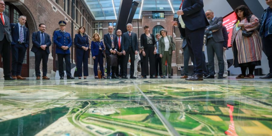 Bundesrat Beat Jans (hinten, in der Mitte) lässt sich vor einer rund 50 Quadratmeter grossen Luftbildaufnahme das Hafengelände von Antwerpen zeigen.