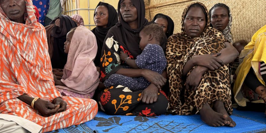 Flüchtlinge aus dem Sudan warten in der tschadischen Grenzstadt Adré auf dem Gelände des Roten Kreuzes auf den Weitertransport in ein Flüchtlingslager. Hinter einigen von ihnen lieg...