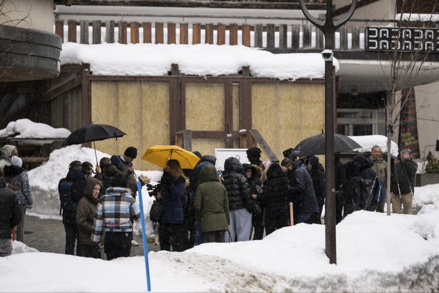 Vor der abgebrannten Bar gedenken mehrere Dutzend Menschen den Opfern der Brandkatastrophe.