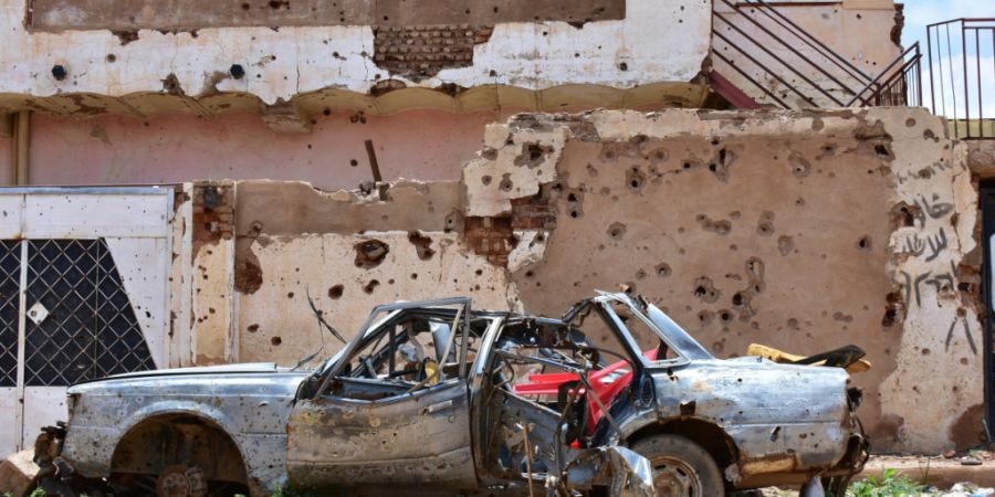 ARCHIV - ARCHIV. Ein zerstörtes Auto steht vor einem Haus voller Einschüsse. Jetzt sind zahlreiche Zivilisten bei einem Drohnenangriff auf einen Marktplatz ums Leben gekommen. Foto: M...