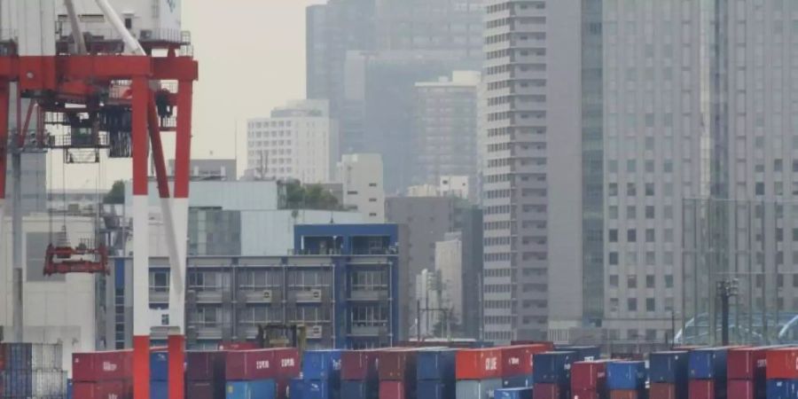 In einem Hafen in Tokio werden Container gestapelt. Foto: Koji Sasahara/AP/dpa