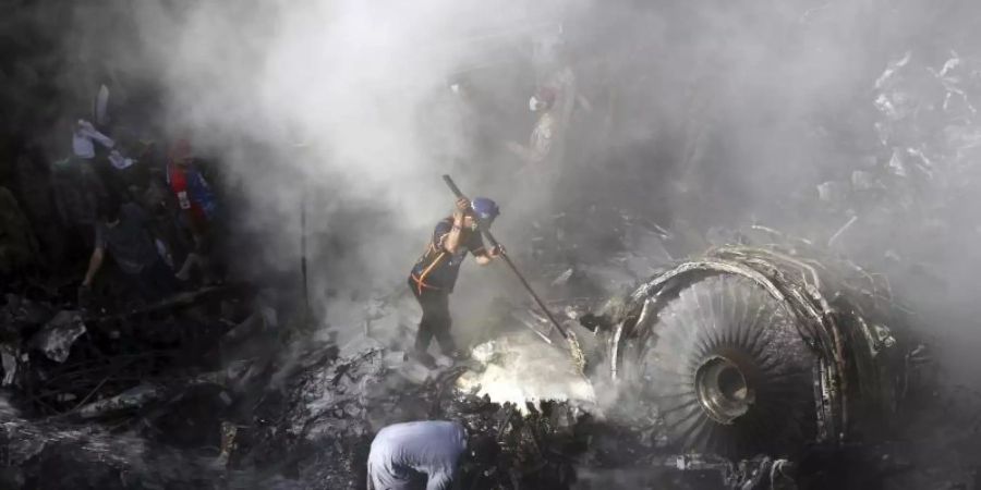 Helfer und Einsatzkräfte suchen nach dem Absturz einer Maschine der Fluggesellschaft Pakistan International Airlines (PIA) in Karatchi nach Überlebenden. Foto: Fareed Khan/AP/dpa/Archiv