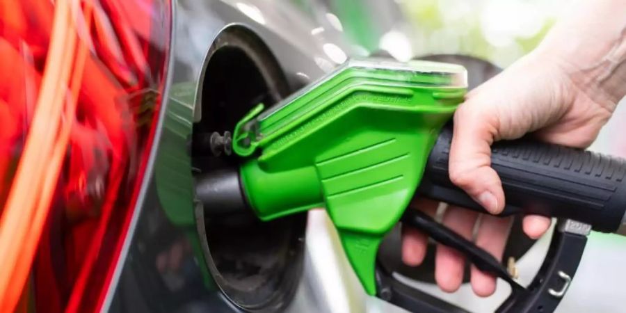 Eine Frau hält an einer Tankstelle an einer Zapfsäule eine Zapfpistole in der Hand und betankt ein Auto. Foto: Sven Hoppe/dpa
