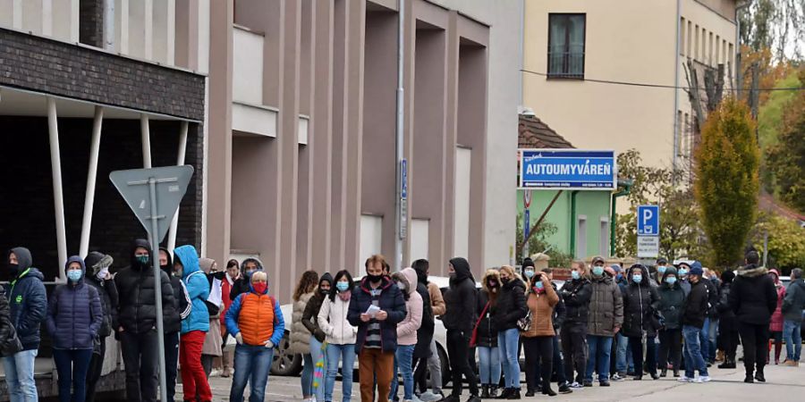 Zahlreiche Menschen mit Gesichtsmaske warten in einer Schlange, um sich auf das Coronavirus testen zu lassen. Foto: Edmund ÷rzsik/TASR/dpa