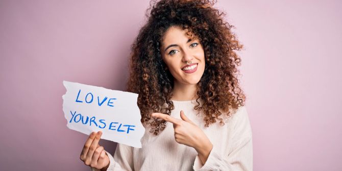 Frau mit Locken hält Schild hoch: Love yourself.