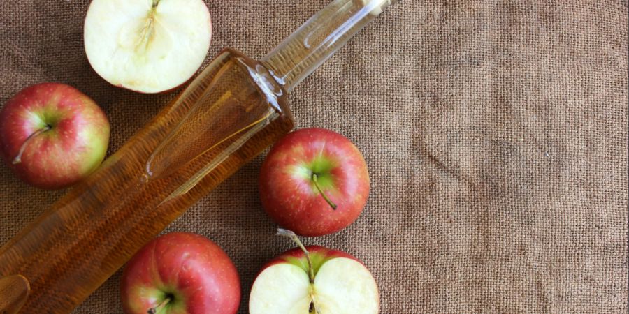 Flasche Apfelessig zwischen Äpfeln