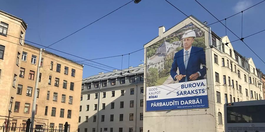Ein Wahlplakat der Partei «Gods kalpot Rigai» (Es ist eine Ehre Riga zu dienen) mit einem Porträt des bisherigen Bürgermeisters Olegs Burovs hängt an einer Hauswand in der lettischen Hauptstadt Riga. Foto: Alexander Welscher/dpa
