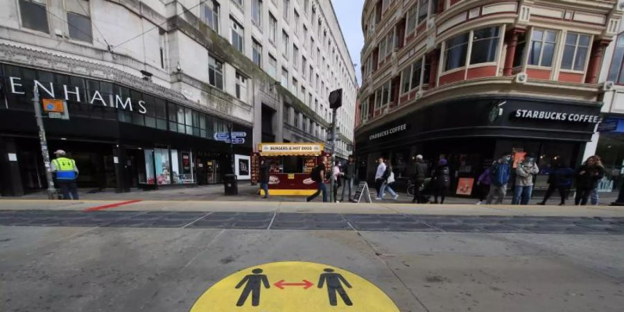 Ein Leitschild auf dem Bürgersteig weist in Manchester auf die Beachtung der Mindestabstände hin. Foto: Danny Lawson/PA Wire/dpa