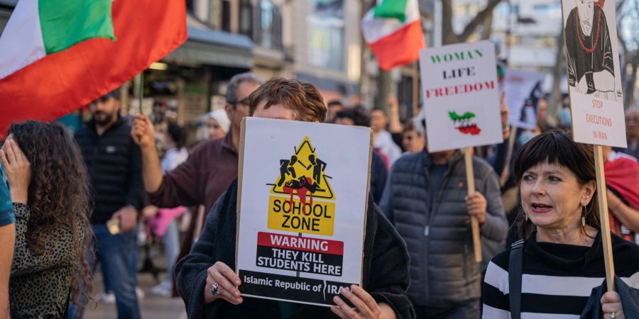 Demonstranten protestieren in Barcelona mit Plakaten und Fahnen gegen eine mutmassliche Vergiftungswelle in Schulen in Iran.