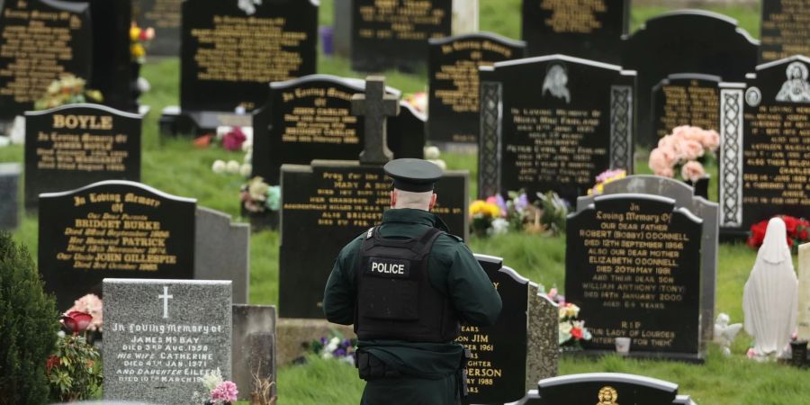 Ein PSNI-Polizist patrouilliert auf dem Stadtfriedhof von Londonderry. Kurz vor der Ankunft von US-Präsident Biden in Nordirland fand die Polizei dort vier mutmassliche Rohrbomben.