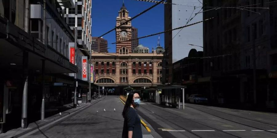 Eine Person mit Gesichtsmaske geht über die Strasse in Melbourne. Foto: James Ross/AAP/dpa