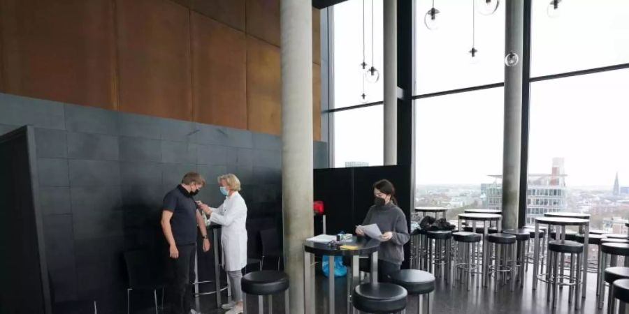 Ein Mann lässt sich in der Skyline Bar 20up im 20. Stock des Empire Riverside Hotels am Hamburger Hafen impfen. Foto: Marcus Brandt/dpa