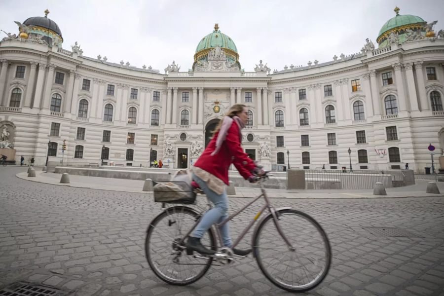 Eine Velofahrerin fährt durch das menschenleere Wien.