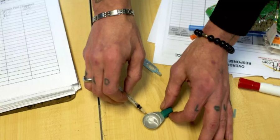 Heroin-Abhängiger illustriert Aufziehen einer Spritze