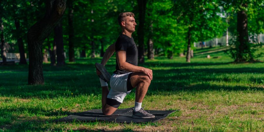 Mann macht Dehnübungen im Park