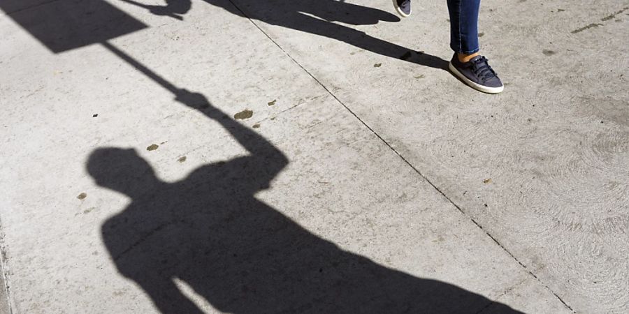 Schatten von streikenden Schauspielern, darunter SAG-AFTRA-Mitglied Isaac Burks (l) klopfen ihre Streikpostenschilder vor den Netflix-Studios zusammen. Schauspieler und Filmstudios in Hollywood haben ein «vorläufiges Abkommen» erzielt, um den seit knapp vier Monaten dauernden Streik zu beenden. Foto: Chris Pizzello/Invision/AP/dpa