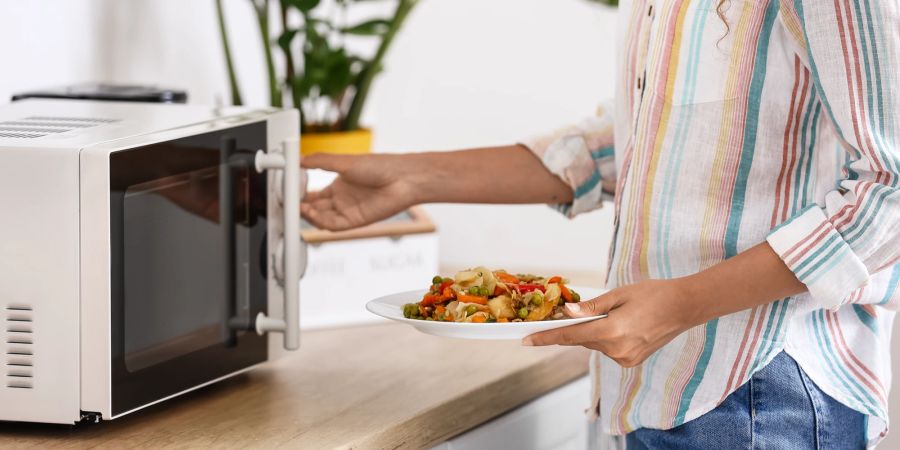 Frau mit Essen an Mikrowelle