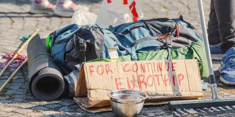 Reiserucksack auf der Strasse mit einem Schild, mit der Bitte um Spenden für eine Europareise.