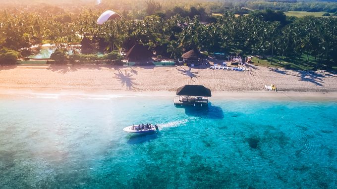 Suche dir ein Plätzchen im weissen, warmen Sand und kaufe dir eine Kokosnuss von einem Händler. So geht Urlaub in Mauritius. Flic-en-Flac Strand